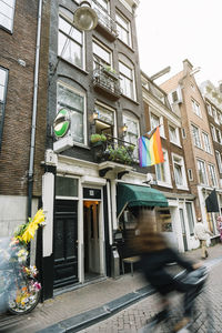From below of lgbt rainbow flag hanging on brick residential building with windows and forged balconies in amsterdam