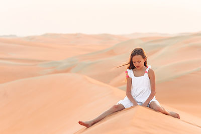 Woman sitting on sand dune in desert