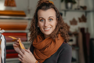 Engaged and smiling fashion designer with curly hair examining a material sample in a shop