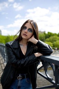 Portrait of young woman standing against trees