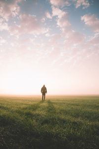 Man standing on field against sky during sunset