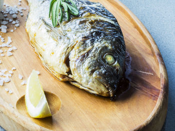 Close-up of fresh fish with lemon slice and salt on cutting board