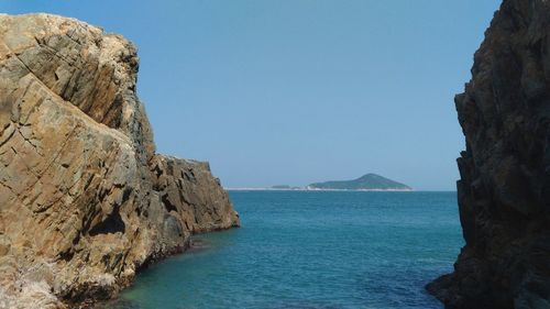 Rock formations in sea against clear blue sky