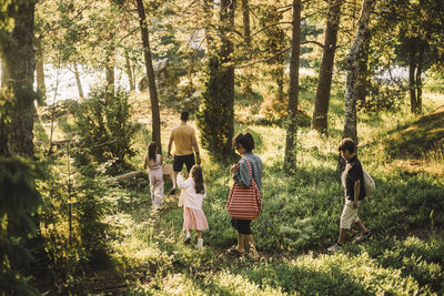 High angle view of family strolling together in forest during picnic