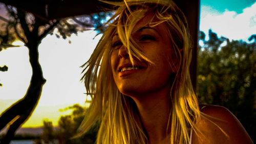 Close-up portrait of smiling young woman against sky