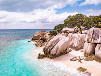 Rock formation on beach against sky, couple beach la digue seychelles 