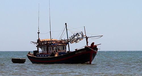Boats in sea against clear sky