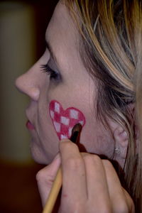 Close-up of woman making heart shape on cheek