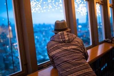 Rear view of man looking through window