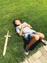 High angle view of boy lying on grassy field