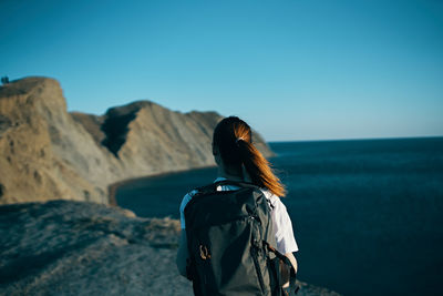 Rear view of woman looking at sea against clear blue sky