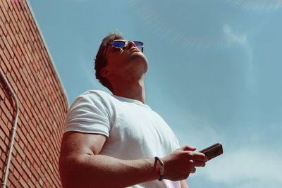 Low angle view of man using mobile phone against sky