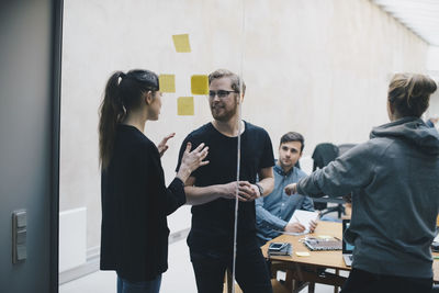 Computer programmers discussing in office seen through glass