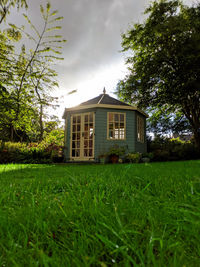 House and trees on field against sky