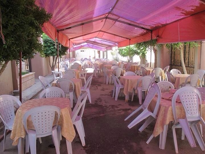 chair, empty, table, absence, in a row, sitting, large group of objects, group of objects, ceiling, seat, restaurant, arrangement, dining, repetition, city life, arranged, red, order, many, long, silence