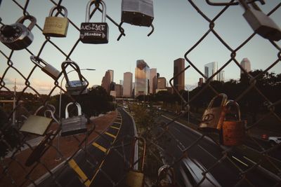 Cityscape seen through chainlink fence against sky