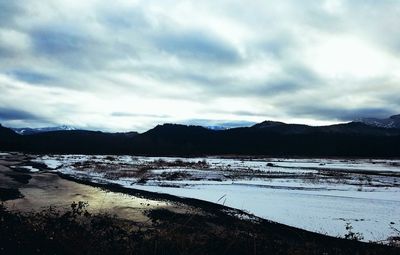 Scenic view of lake by mountains against sky