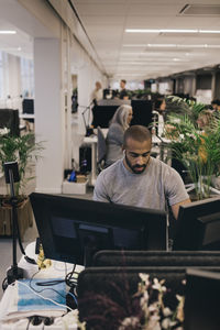 Mid adult businessman working on computers at desk in creative office