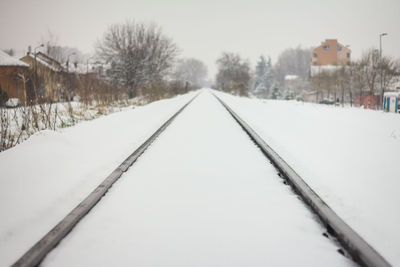 Snow covered railroad tracks against sky during winter