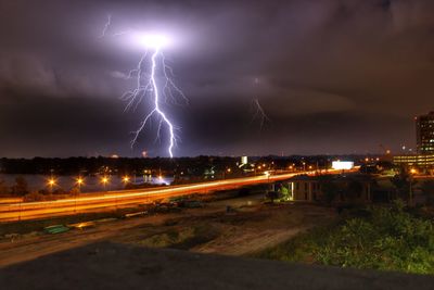 Lightning over illuminated cityscape against dramatic sky