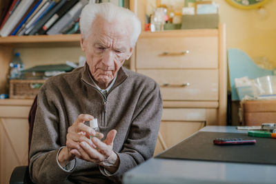 Senior man using hand sanitizer at home