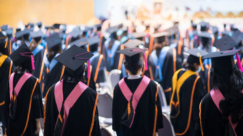 Rear view of people wearing graduation gown standing outdoors