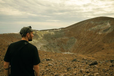 Rear view of man standing on mountain against sky