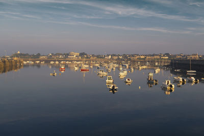 Sailboats in marina by river against sky in city