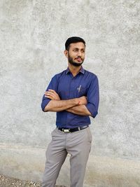 Portrait of young man standing against wall