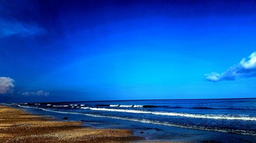 Scenic view of beach against blue sky