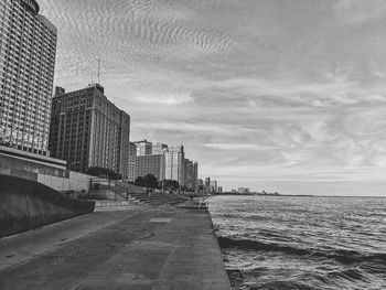 Modern buildings by sea against sky