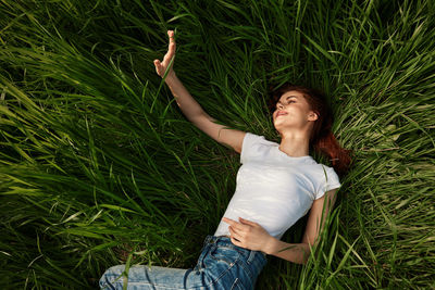 Full length of young woman sitting on grassy field