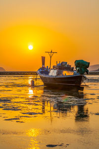 Boats moored on sea against orange sky