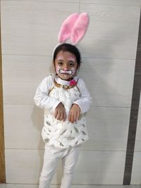 Portrait of smiling girl standing against wooden wall