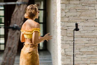 A beautiful girl records her daily blog video on a smartphone mounted on a tripod. side view.