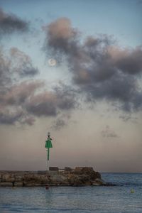 Lighthouse by sea against sky