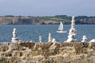 Sailboats on sea shore against sky