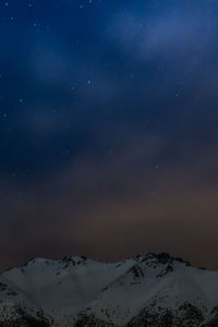 Scenic view of snow covered mountains against sky at night