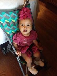 Portrait of cute baby girl sitting on floor at home