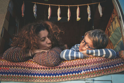 Smiling mother and son in lying camper van