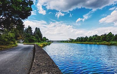 Scenic view of road by trees against blue sky