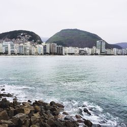 Scenic view of sea by city against clear sky