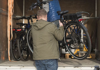 Rear view of man working on bicycle