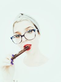 Portrait of woman eating chocolate against white background