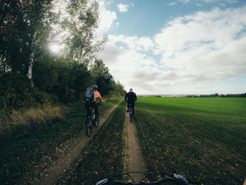 Rear view of man riding bicycle on road against sky