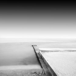 Pier by sea against sky during foggy weather