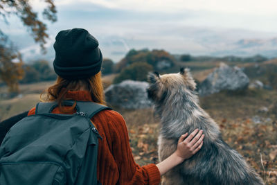 Rear view of woman with dog looking at winter