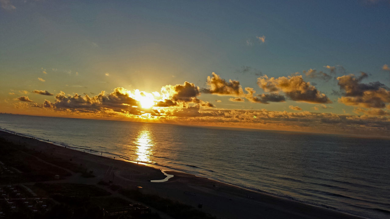 sea, water, sunset, beach, scenics, tranquil scene, horizon over water, sun, beauty in nature, tranquility, reflection, tourism, sand, shore, travel destinations, sky, idyllic, vacations, cloud, sunbeam, nature, non-urban scene, coastline, back lit, majestic, orange color, moody sky, seascape, outdoors, cloud - sky, atmosphere, dramatic sky, cloudscape