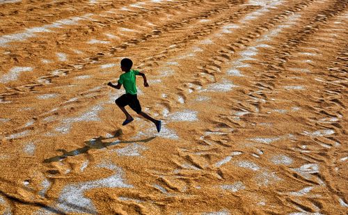 High angle view of boy running on sand