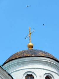 Low angle view of bird flying against clear blue sky